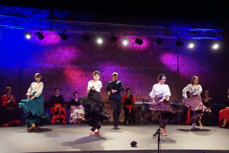 Na scenie grupa kobiet tańczy flamenco.