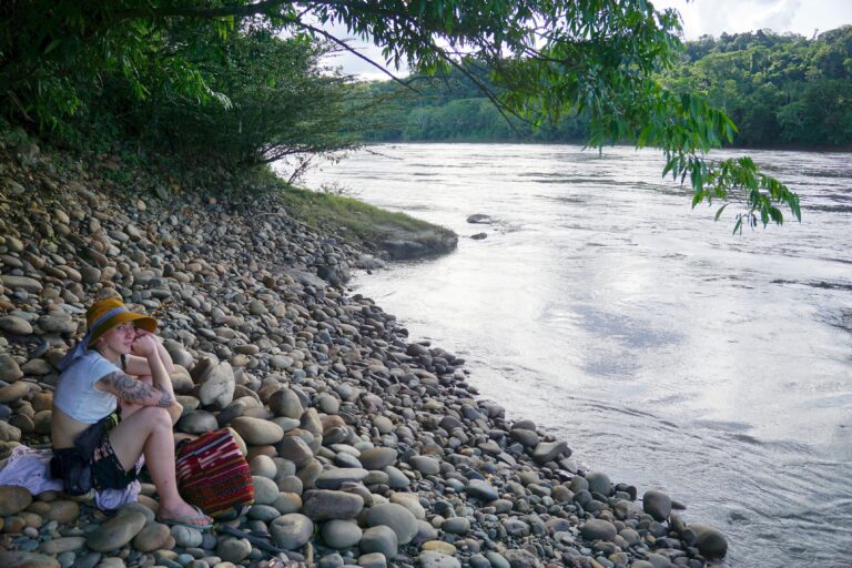 zdjęcie; dziewczyna siedzi na kamiennej plaży nad rzeką w peruwiańskiej Amazonii
