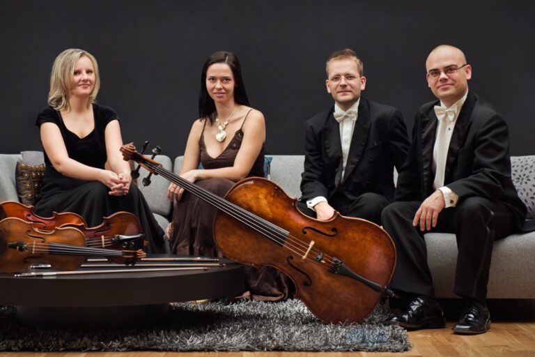 Czterech muzyków muzyki klasycznej z instrumentami siedzących na szarej kanapie.
