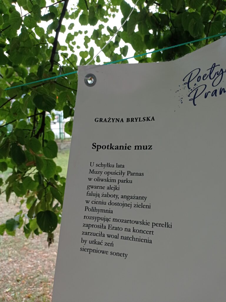 Zdjęcie przedstawia wiszącą na sznurku zalakowaną kartę papieru, na której znajduje się wiersz.